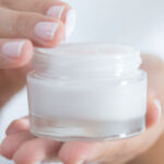 Female hand holding moisturizer in hand, horiztonal